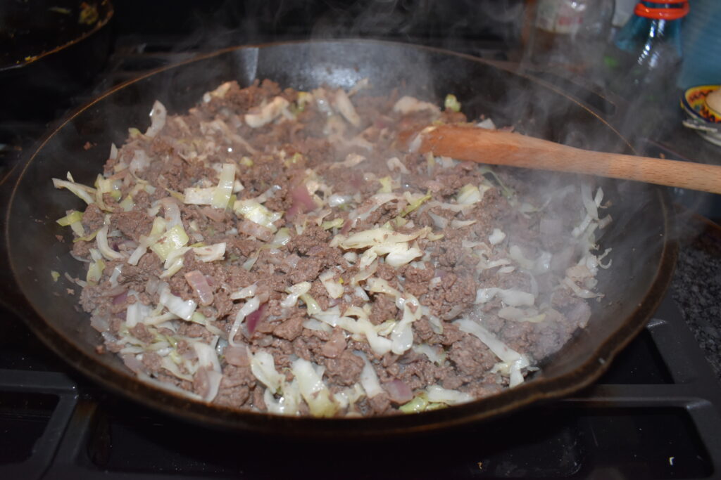 Deer meat browning in skillet with cabbage added