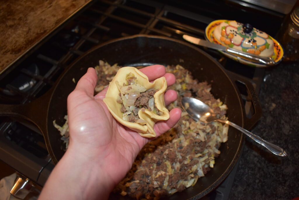 Holding rolled dough to fill with deer and cabbage