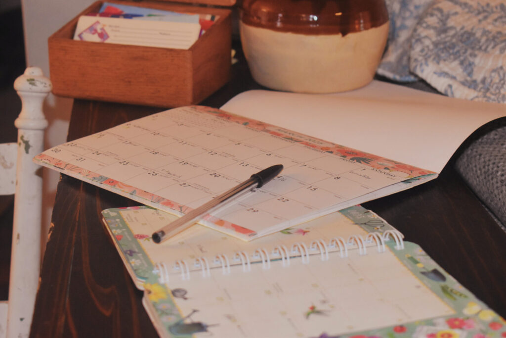 Two calendars on a table with a pen