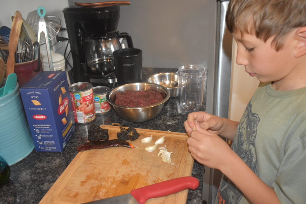 Boy in the kitchen peeling garlic
