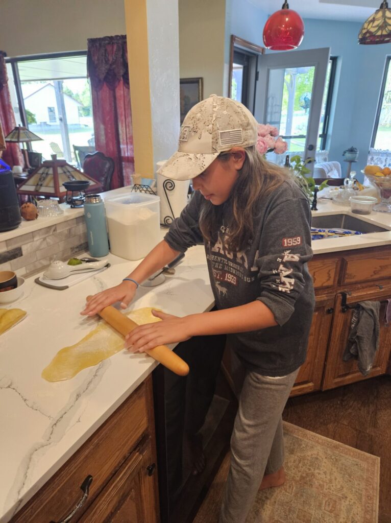 Girl rolling out more pasta
