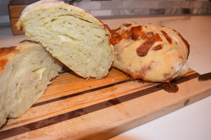 Rosemary cheese sourdough cut in half on a cutting board with cheese oozing out