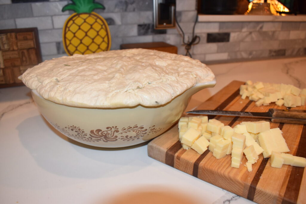 sourdough spilling over the edge of a bowl with cut cheese next to it